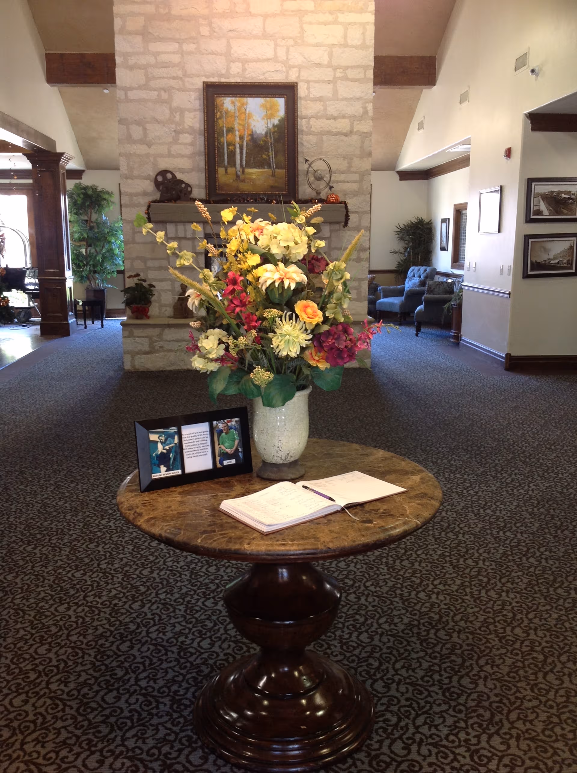 Lobby area with a round marble table, a colorful flower arrangement, and a stone fireplace.