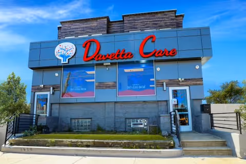 Front exterior of Davetta Care facility with bold red sign and blue facade.