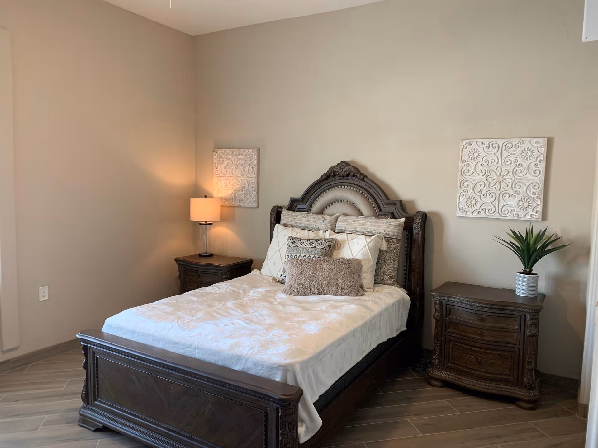 Elegant bedroom featuring a carved dark wood bed, matching nightstands, and soft ambient lighting.