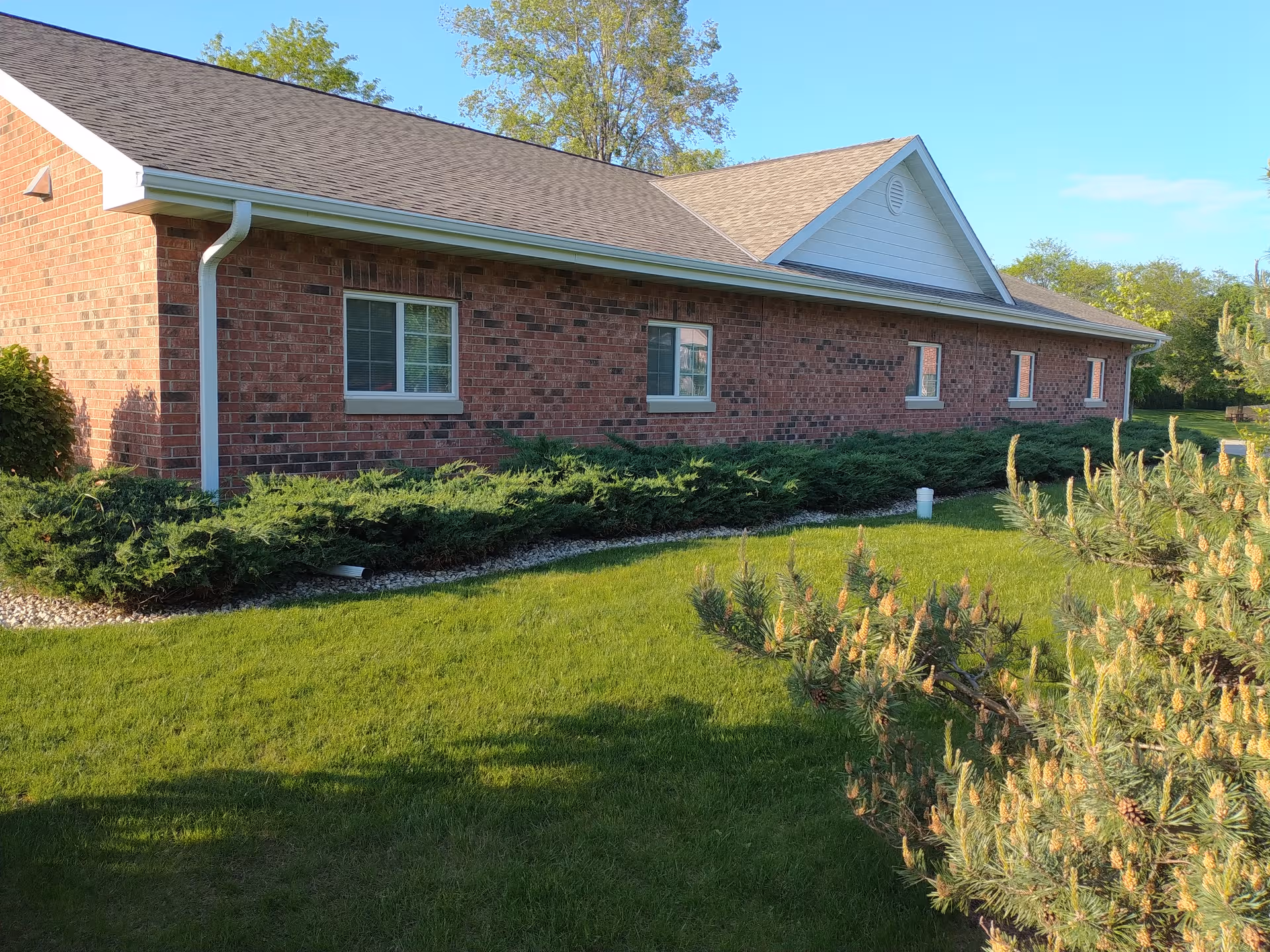 Brick exterior of a single-story senior living building with windows and a well-kept lawn.