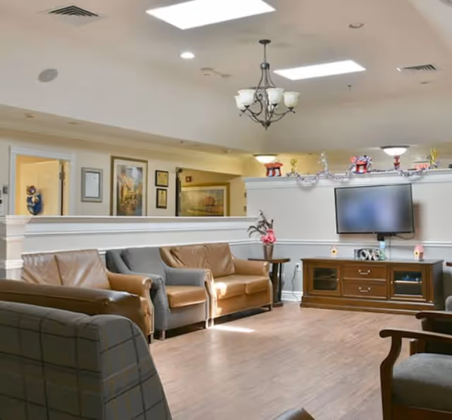 Cozy senior living lounge with sofas, a TV, and decorative accents.