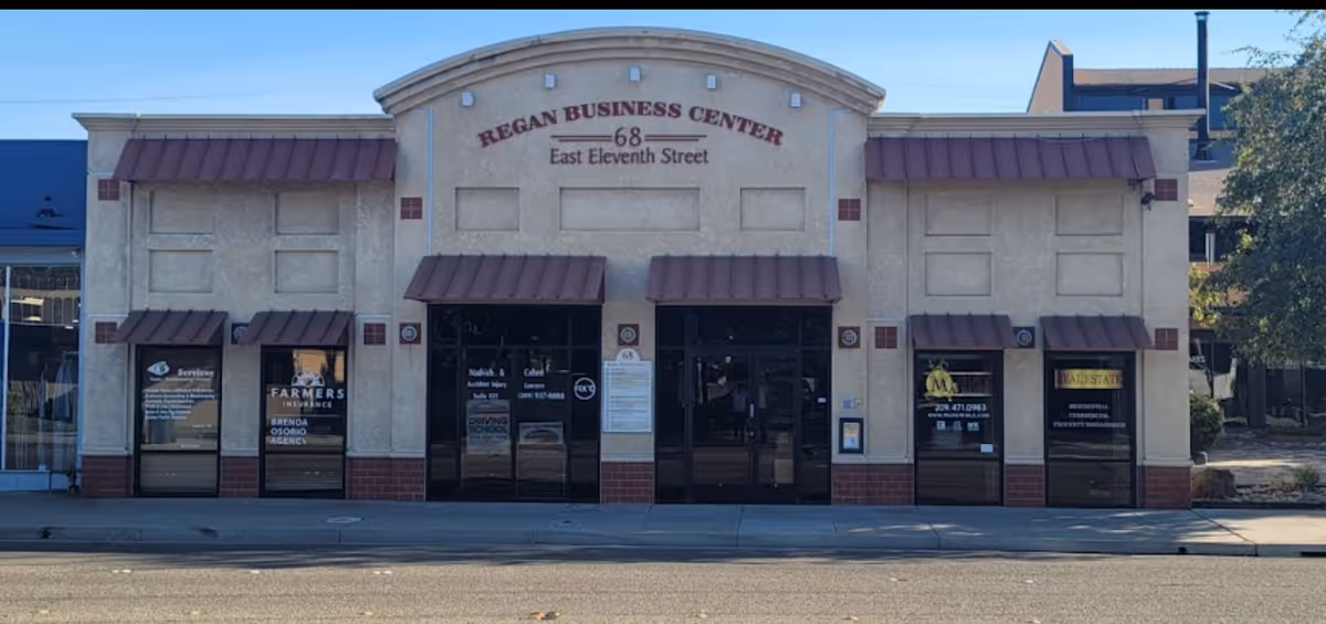 Front view of a commercial building with arched sign and maroon awnings
