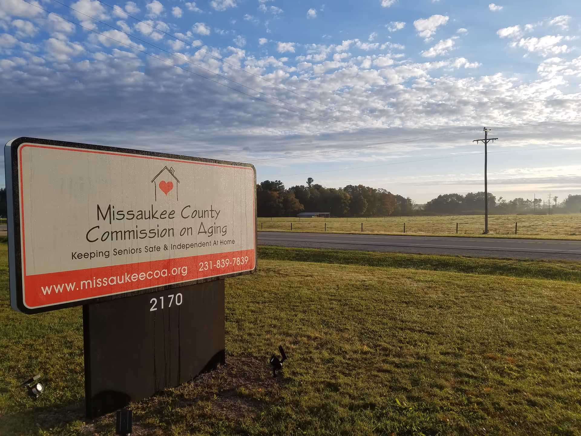 Roadside sign for Missaukee County Commission on Aging beside a grassy field.