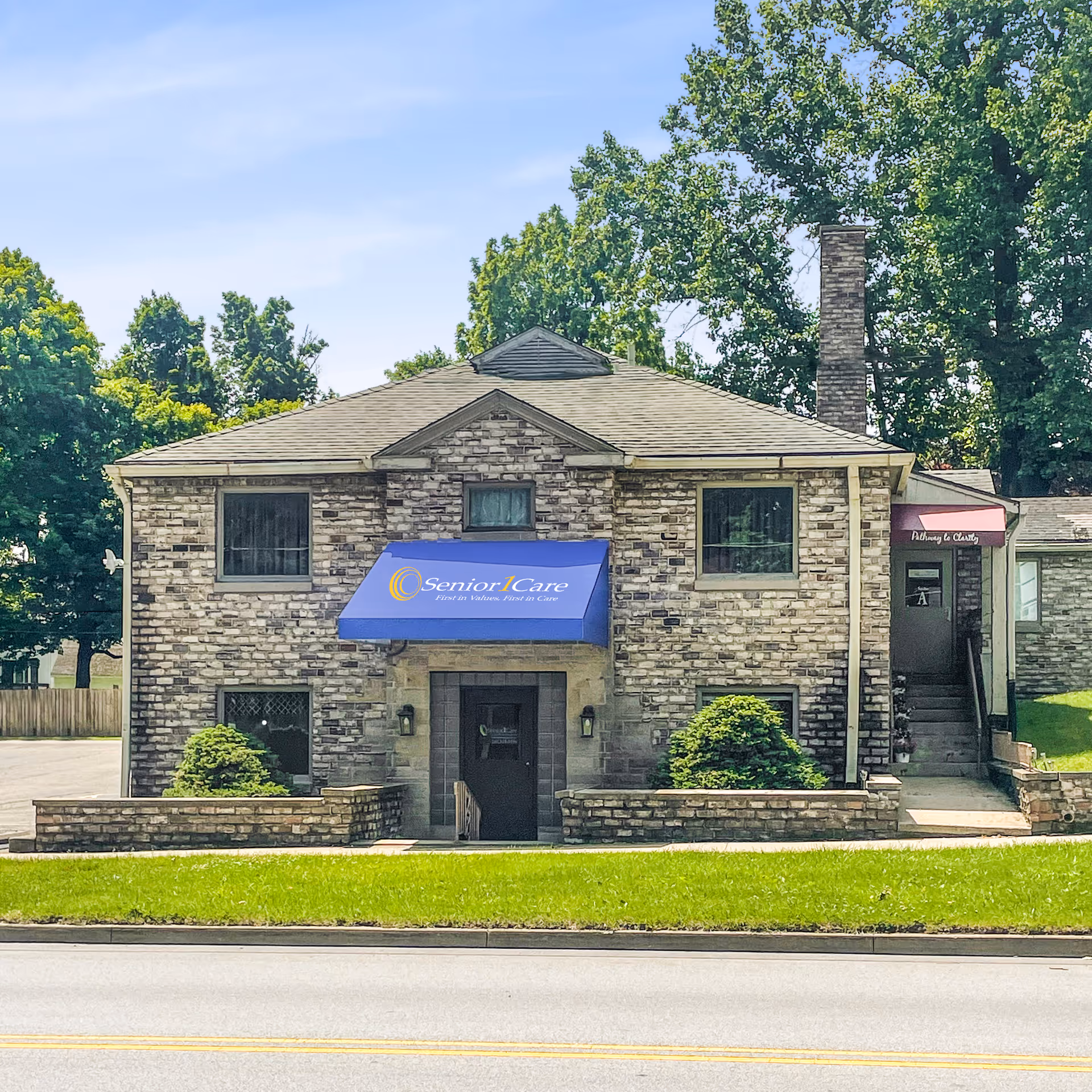 Stone building for Senior1Care with a blue awning, front entrance, and landscaped lawn.