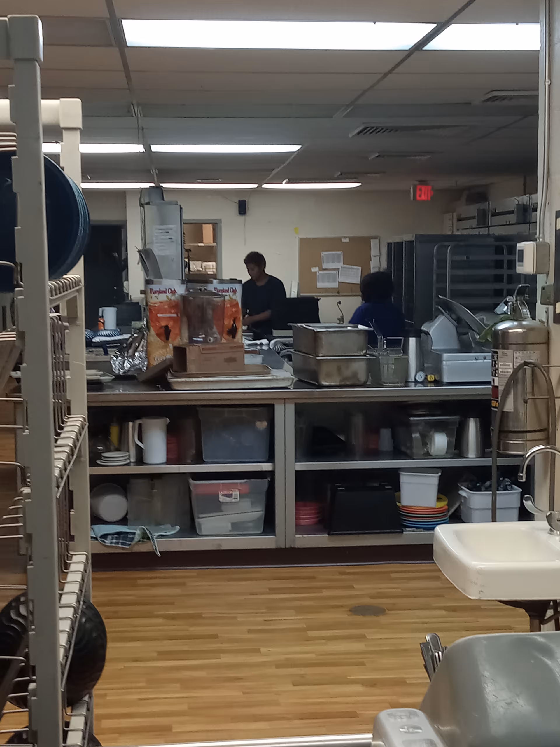 Kitchen area in a nursing home with prep counters, dishes, and staff in the background.