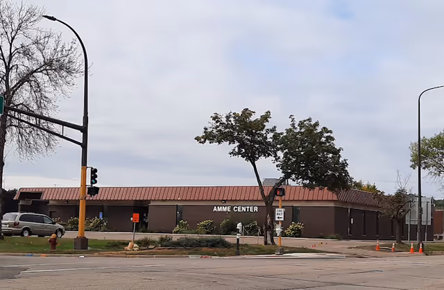 Single-story brick building with a red metal roof on a street corner.