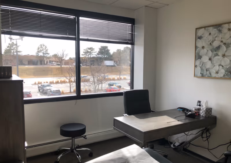 Interior office space inside a senior living facility, featuring a desk, chair, and large window.