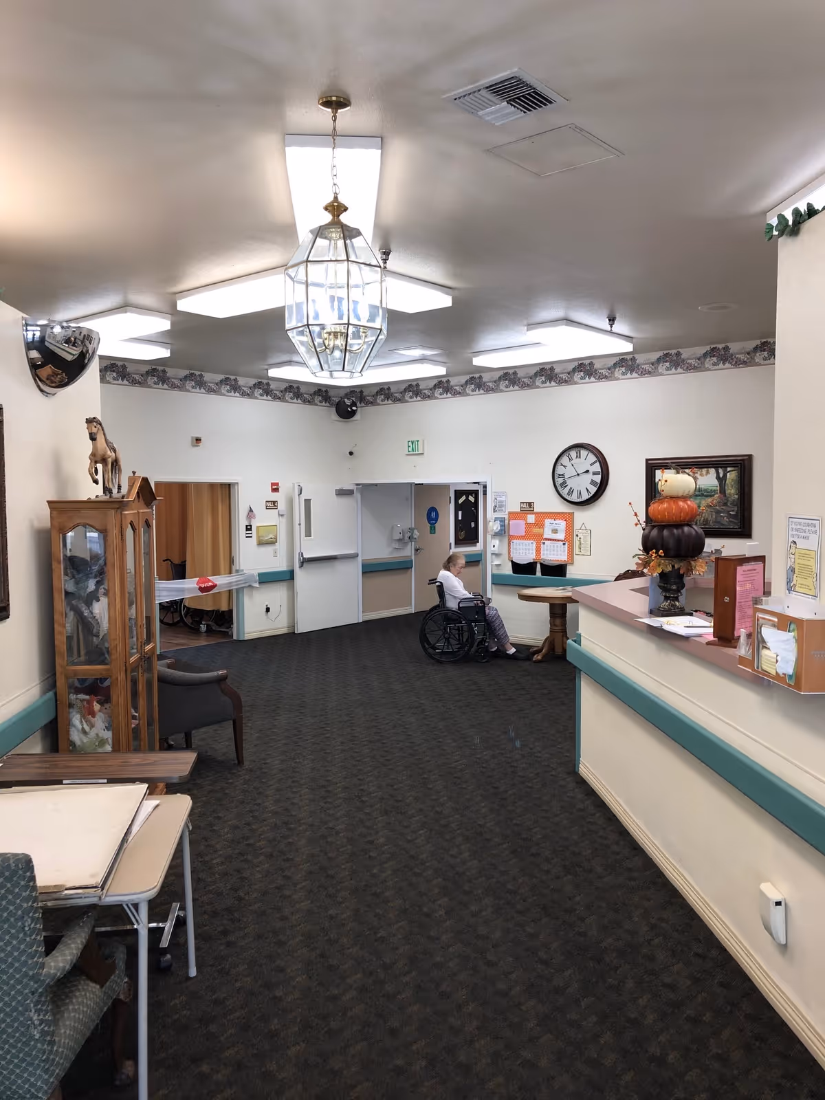 Lobby of a senior living facility with a resident in a wheelchair near a reception desk.