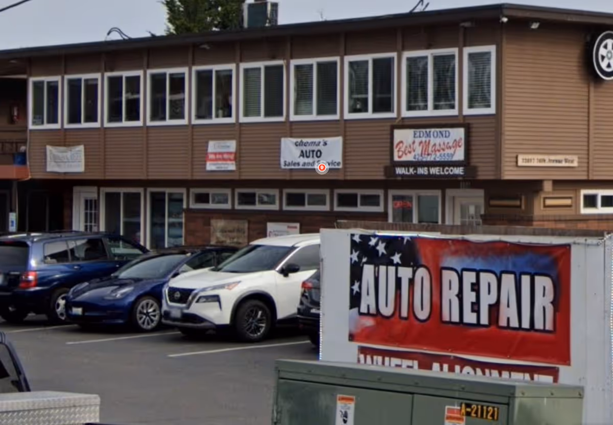Exterior view of a brown two-story commercial building with parked cars and an Auto Repair banner