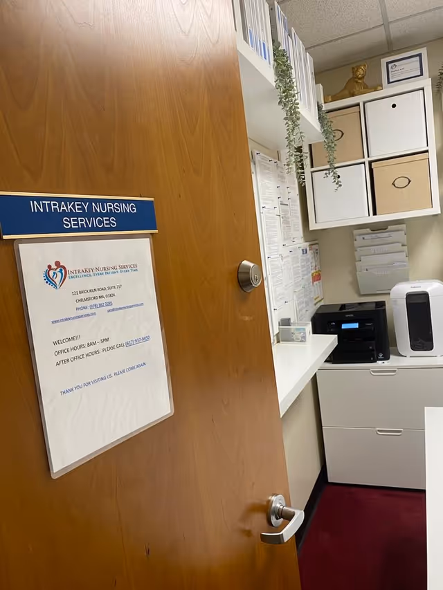 Office doorway displays Intrakey Nursing Services sign with paperwork, shelves, and a printer.