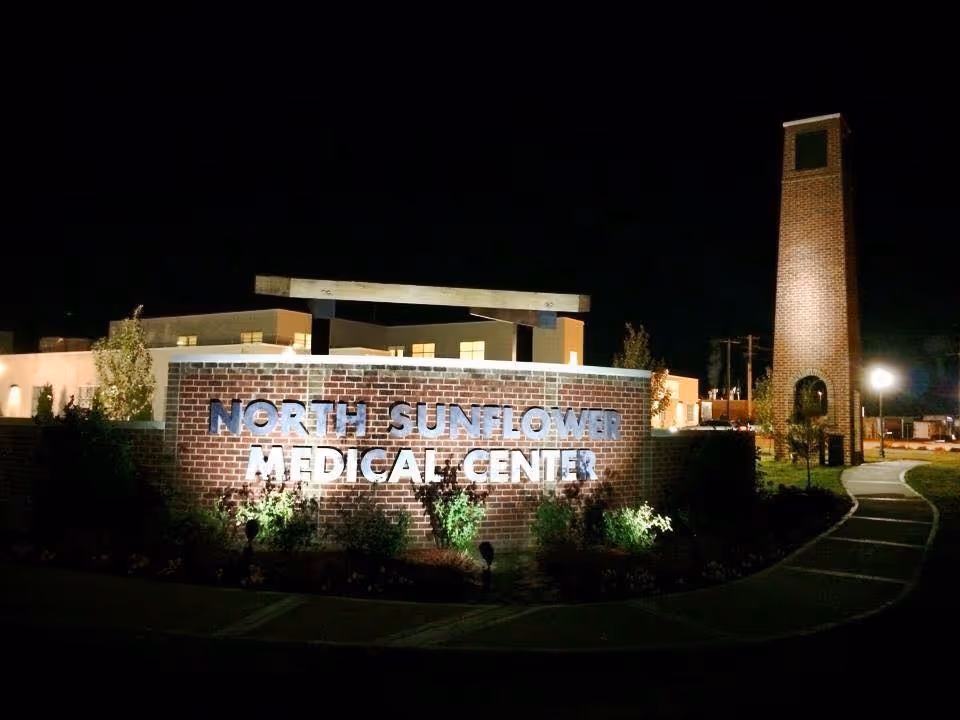 Night exterior view of a brick sign and tall brick tower at a medical facility.