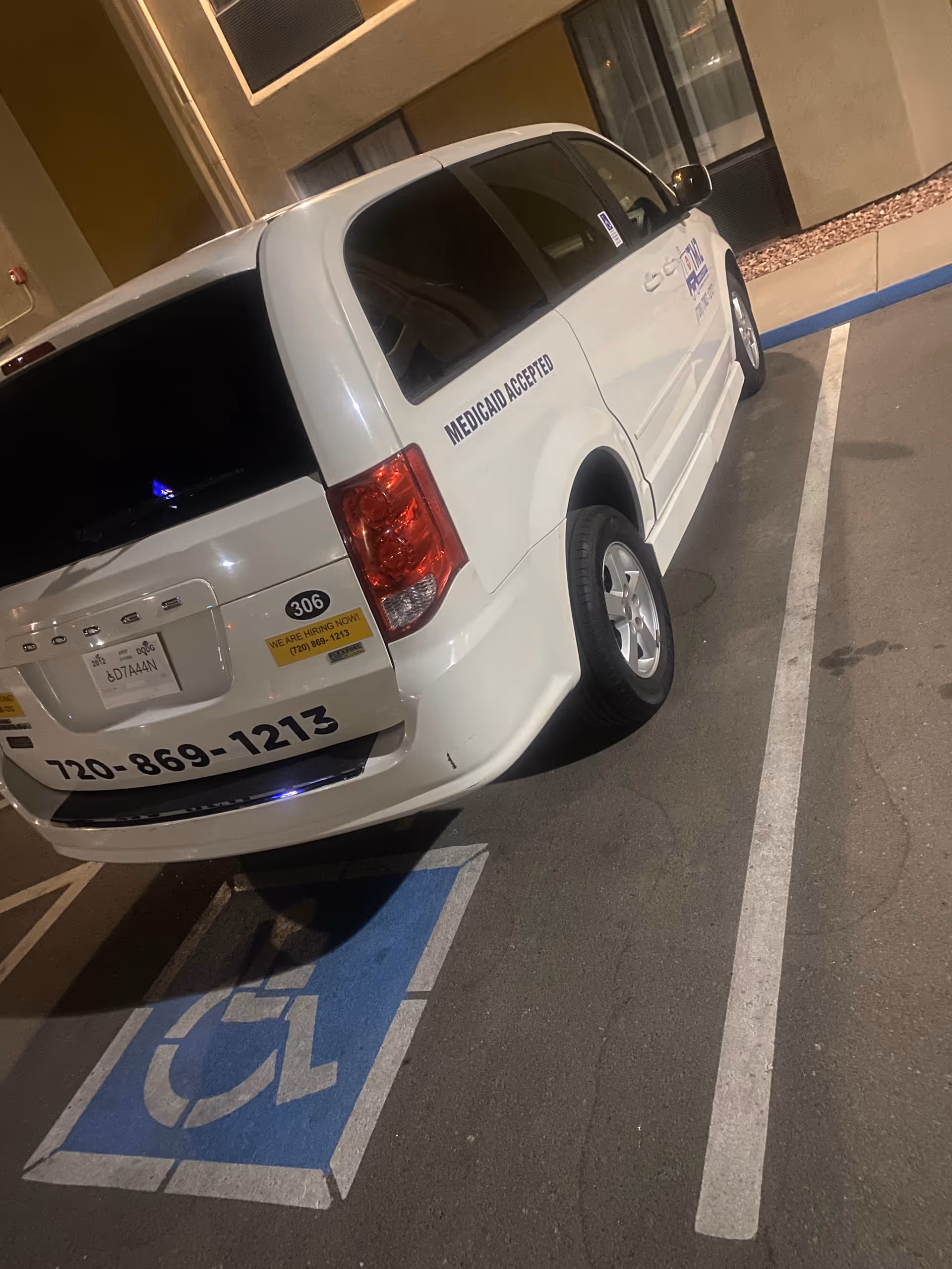 White van with Medicaid Accepted parked in a handicap space outside a building.