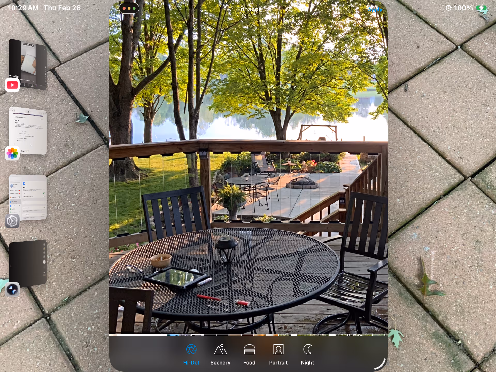 Outdoor deck seating with a metal table and chairs overlooking a lake and trees.