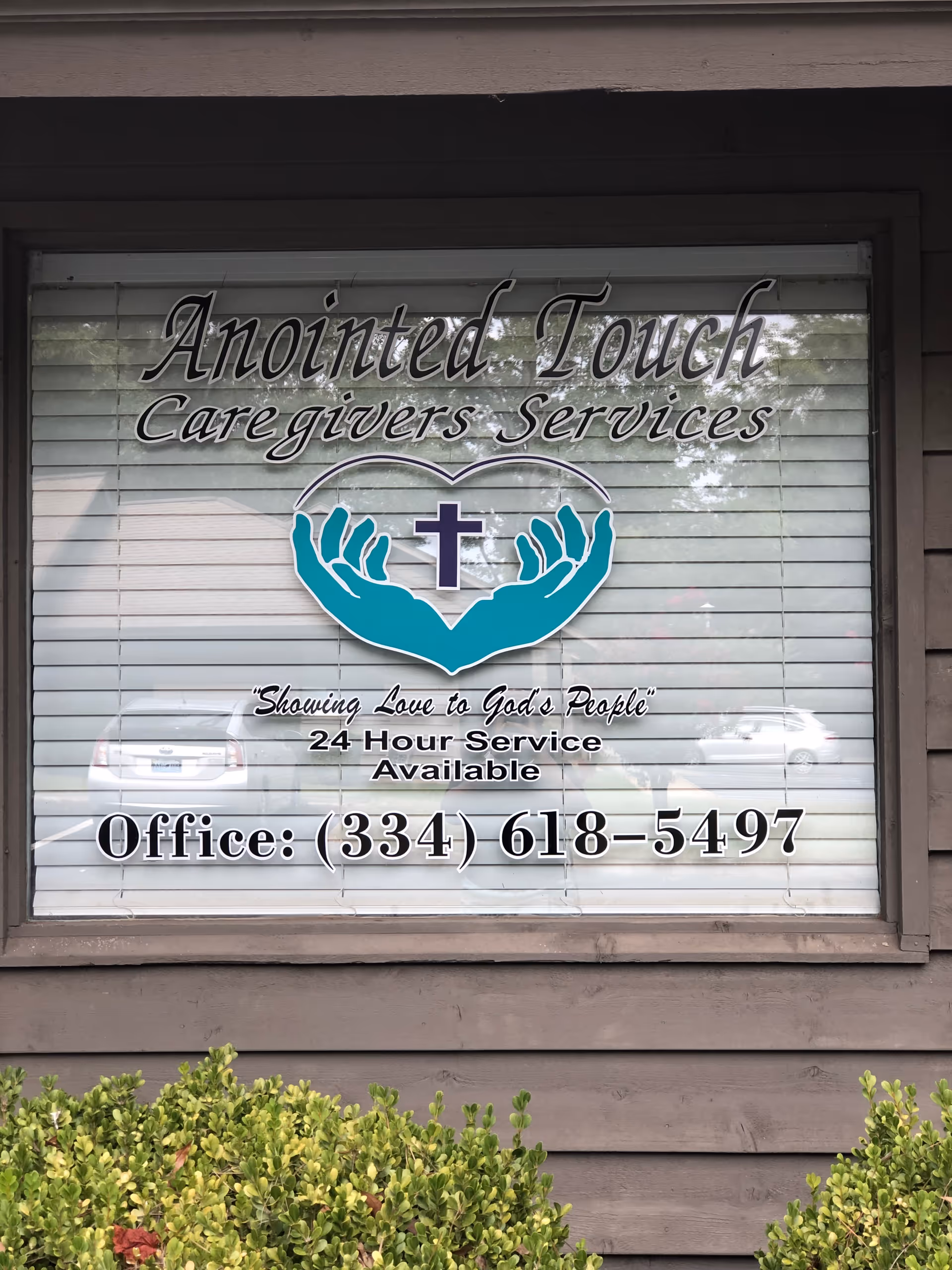 Exterior storefront window displaying Anointed Touch Caregivers Services sign with phone number.