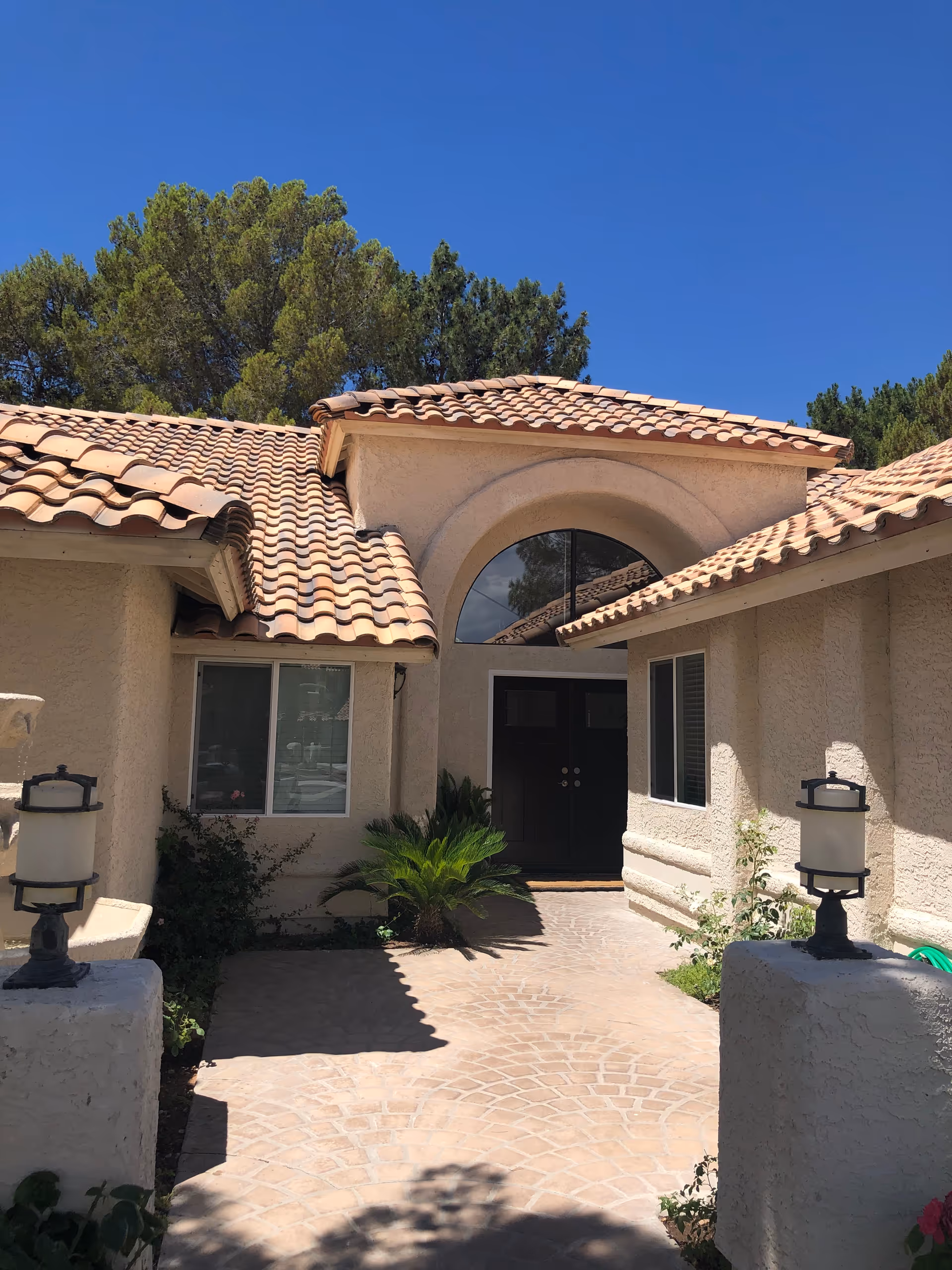 A tan stucco senior living facility entrance with tiled roof and arched window.