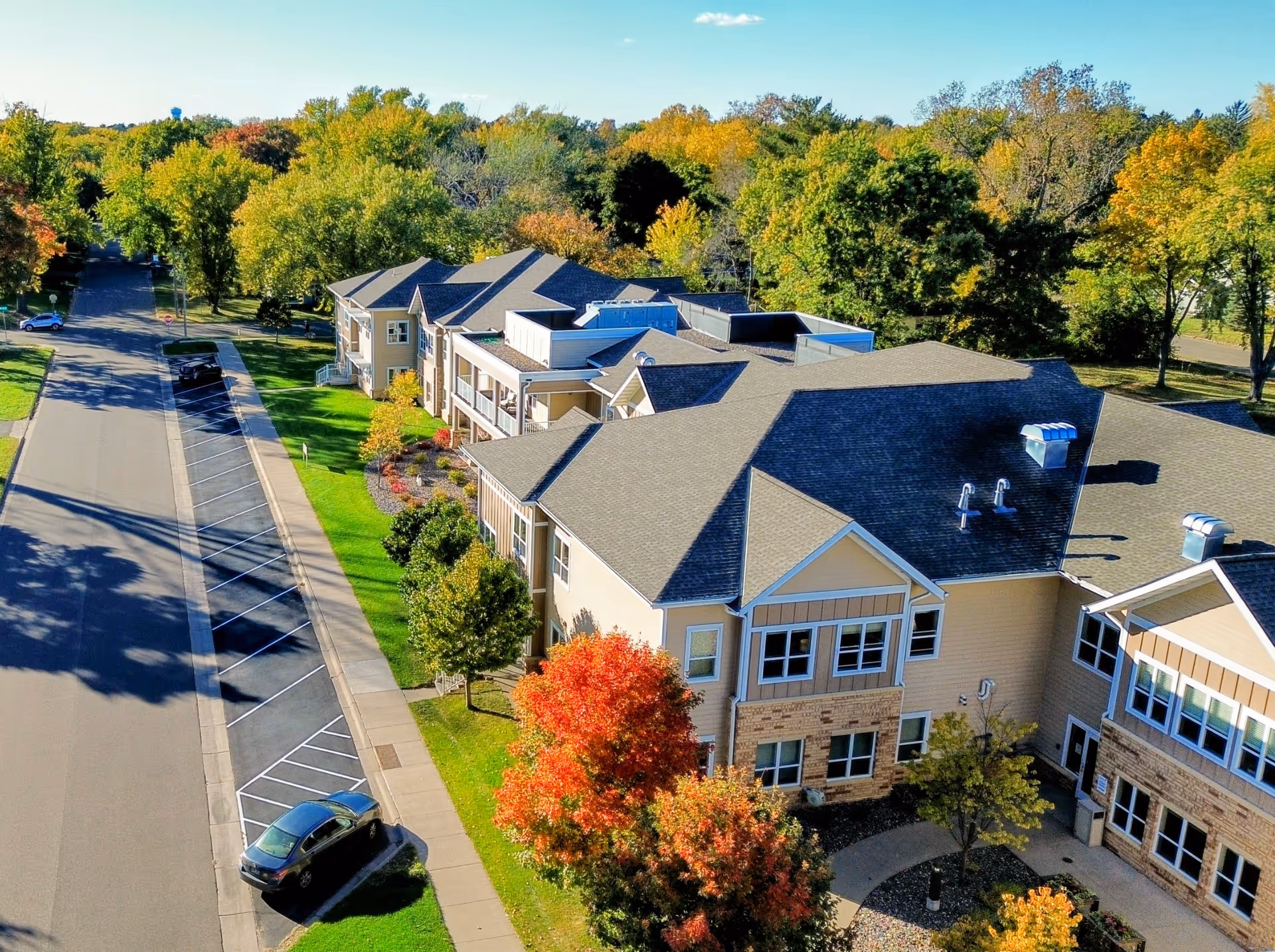 Aerial view of a multi-building senior living campus surrounded by fall-colored trees.