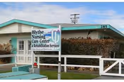 Front exterior of Blythe Post Acute facility with sign and white fence.