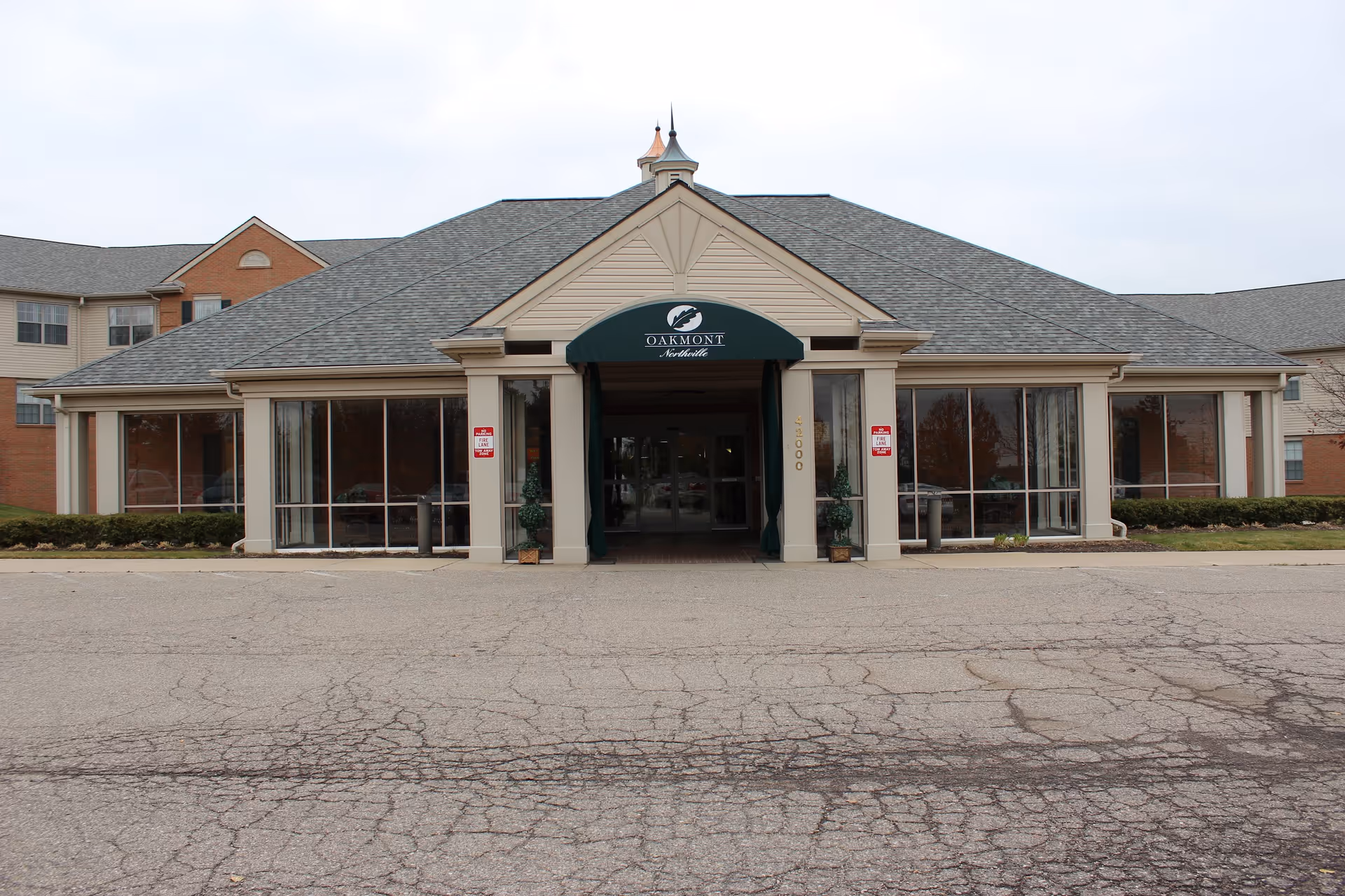 Front view of Oakmont Northville senior living facility entrance with glass windows