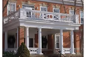 Brick building with a white portico and decorative columns at the entrance.
