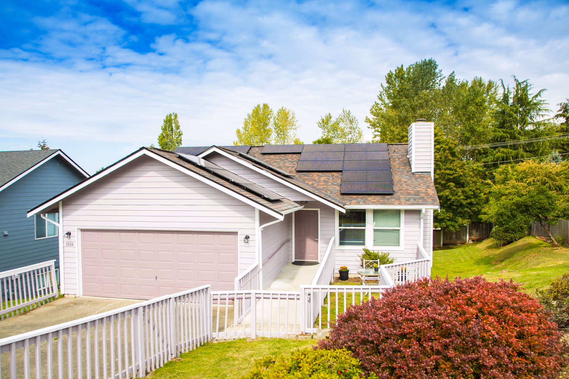 Front view of a pastel-colored house with a two-car garage and solar panels.