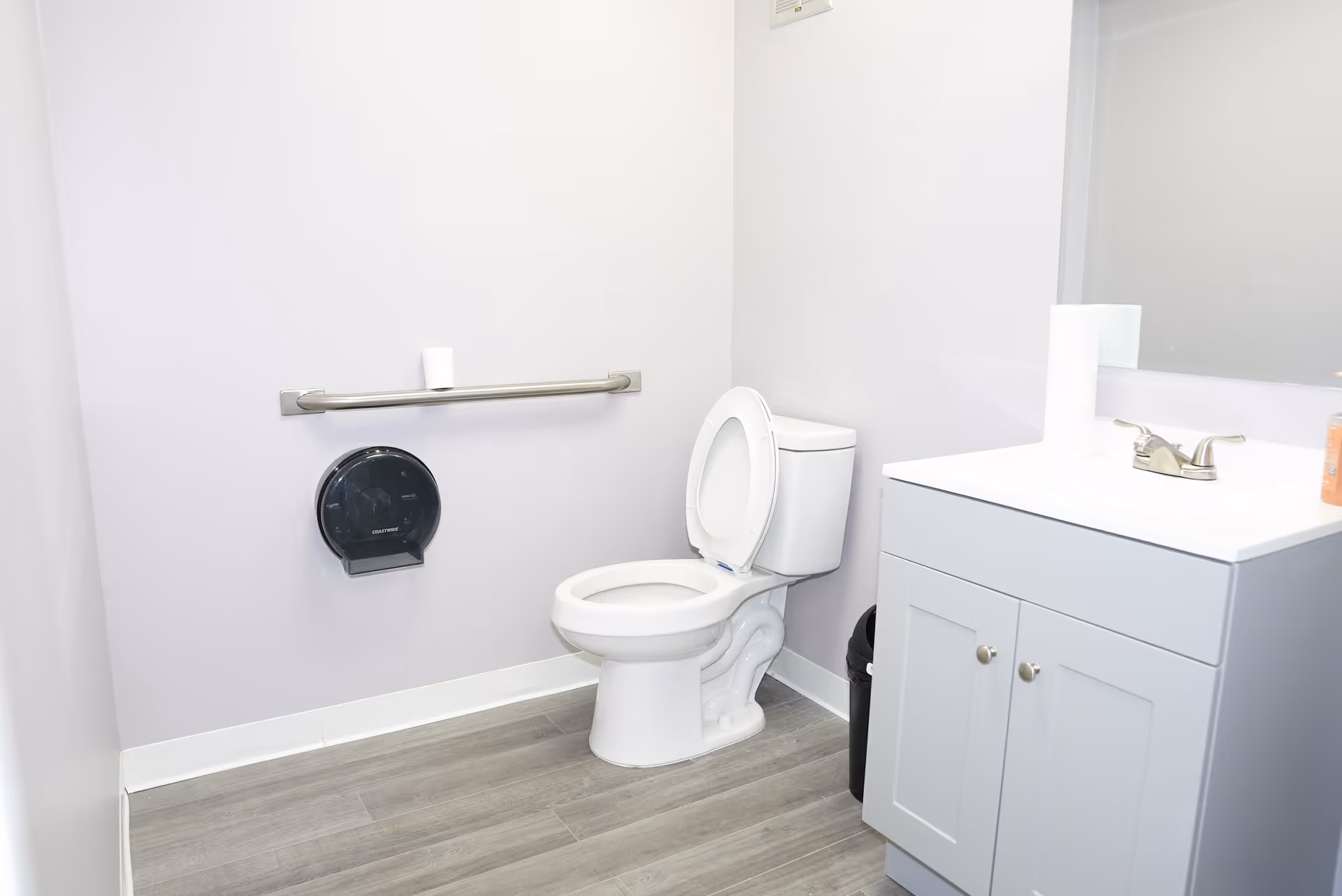 Accessible bathroom with grab bar, toilet, and sink in a clean facility.