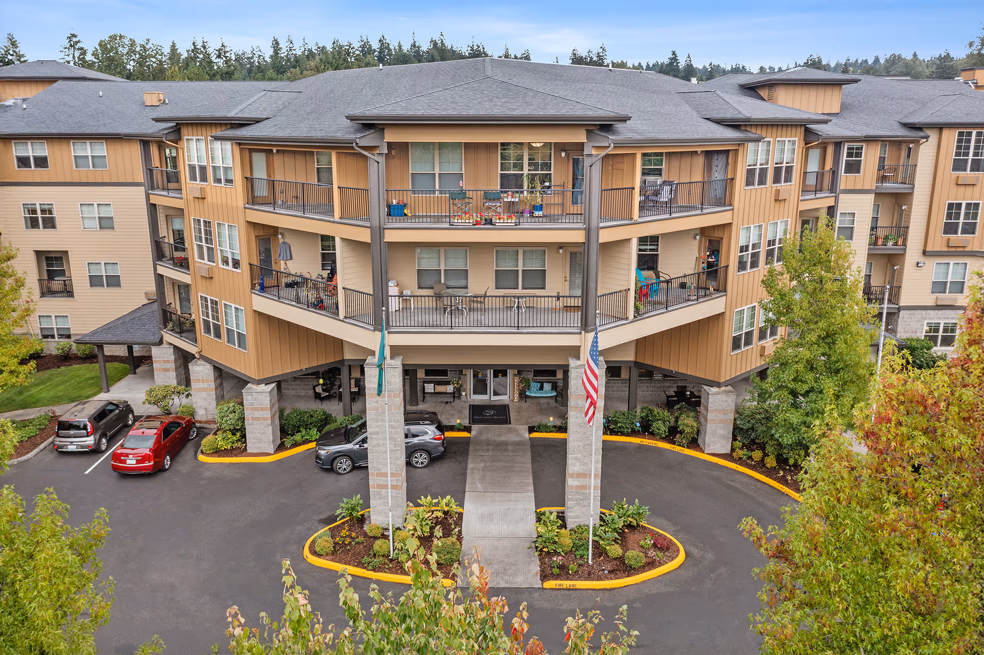 A modern beige multi-story senior living building with a circular driveway and balconies.