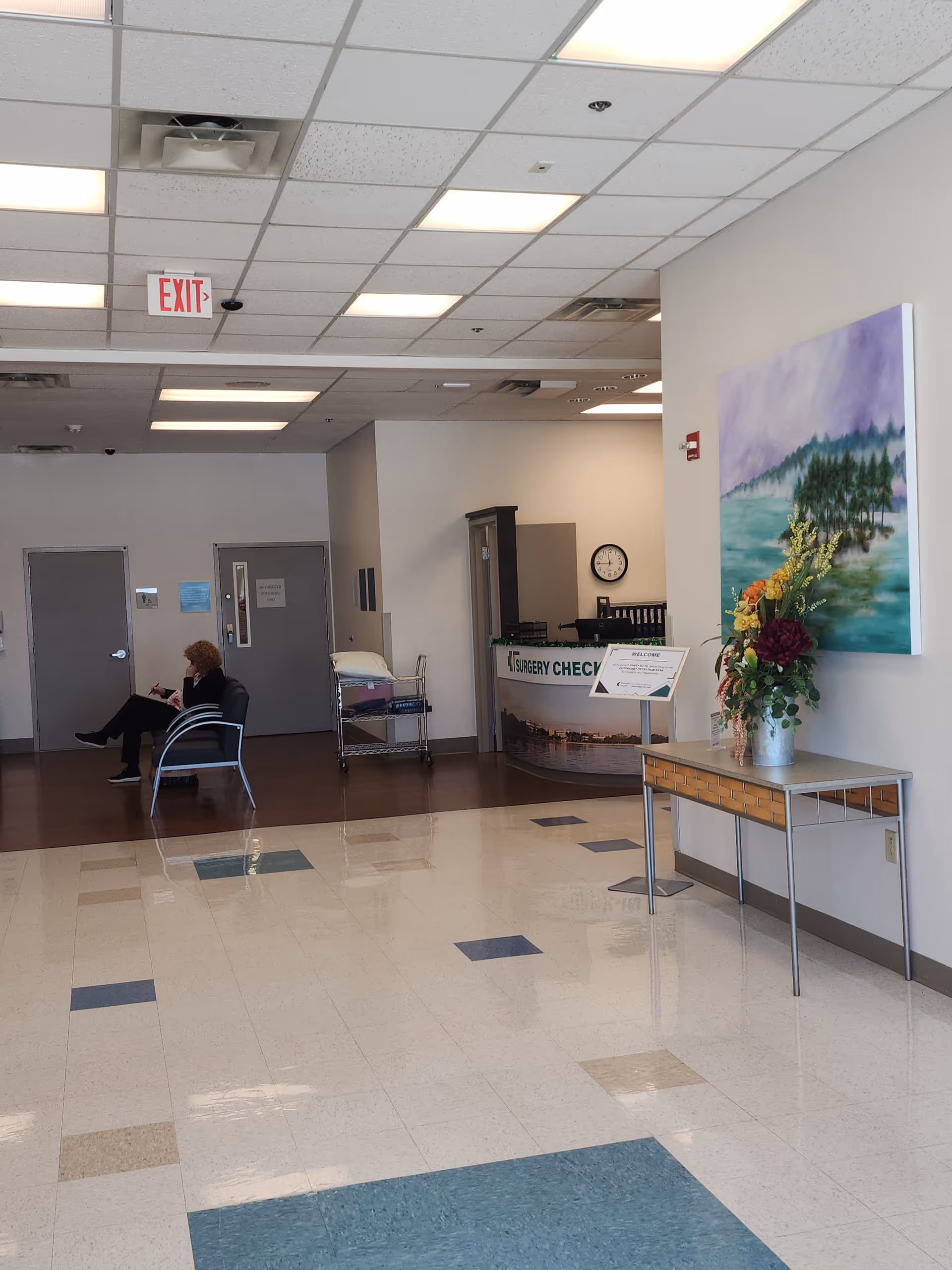 Interior lobby of Manatee Outpatient Services Center with reception desk, flower arrangement, and a seated visitor.