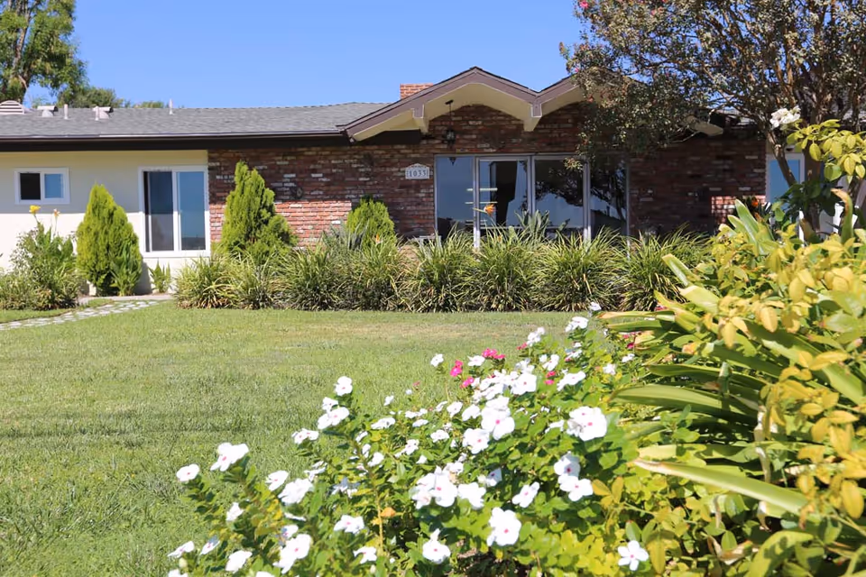 A single-story brick care center with glass doors and lush front landscaping.
