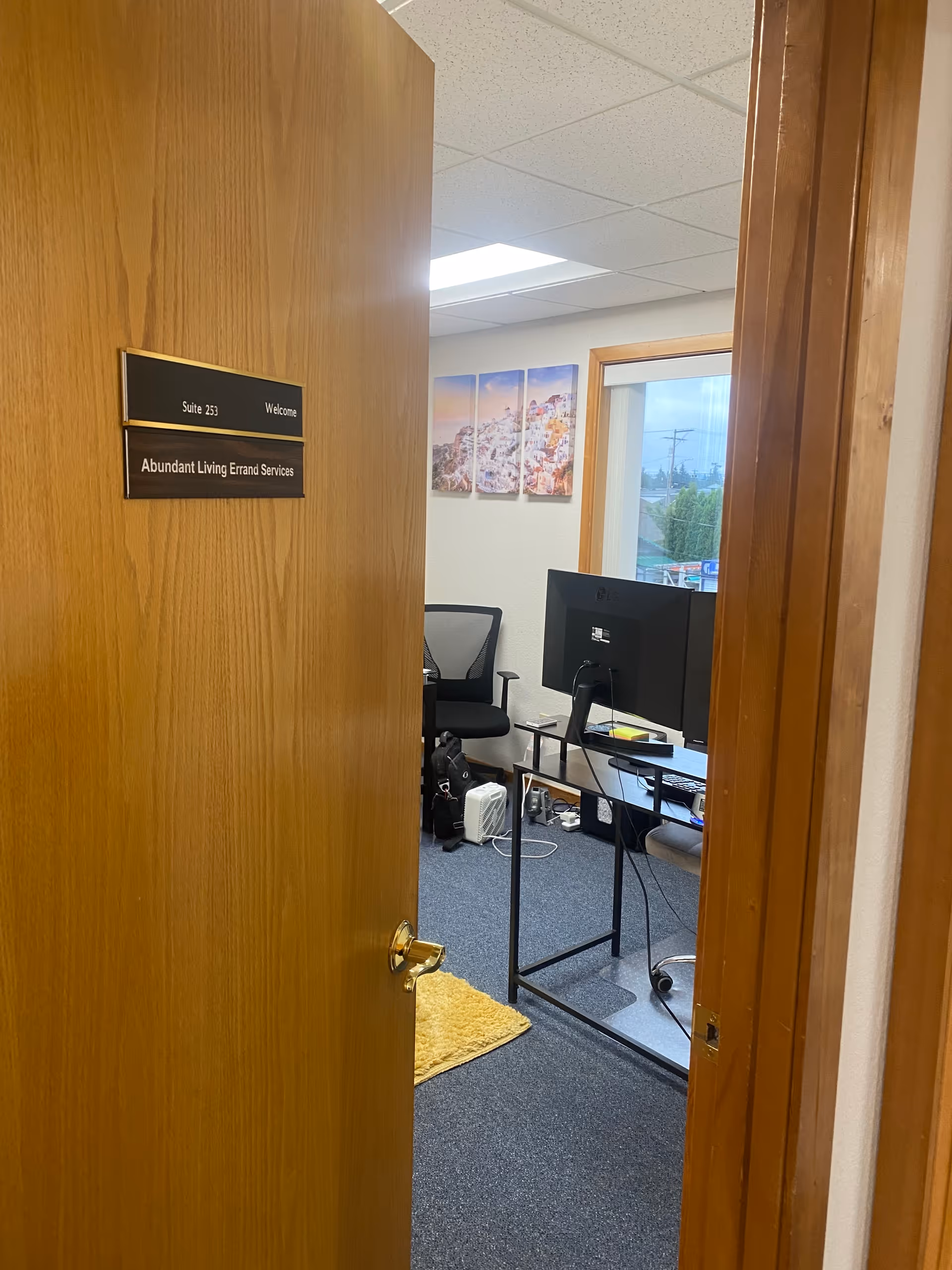 Open door reveals an office with desks, computer, chairs, and Abundant Living Errand Services sign
