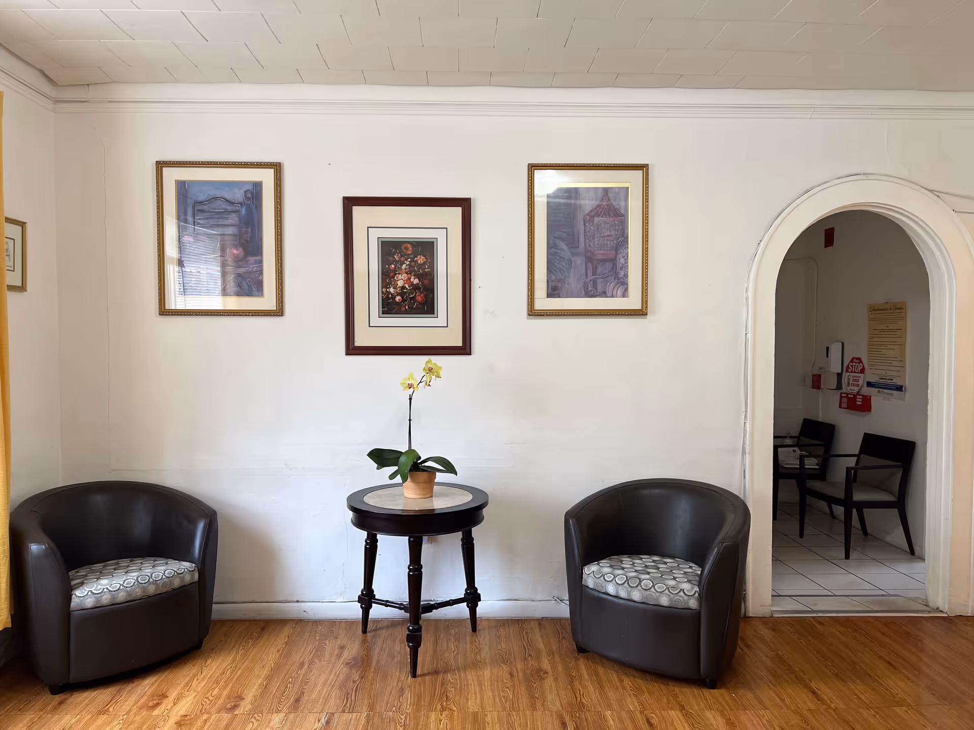 A small lobby seating area with two chairs, a round table, and framed art.