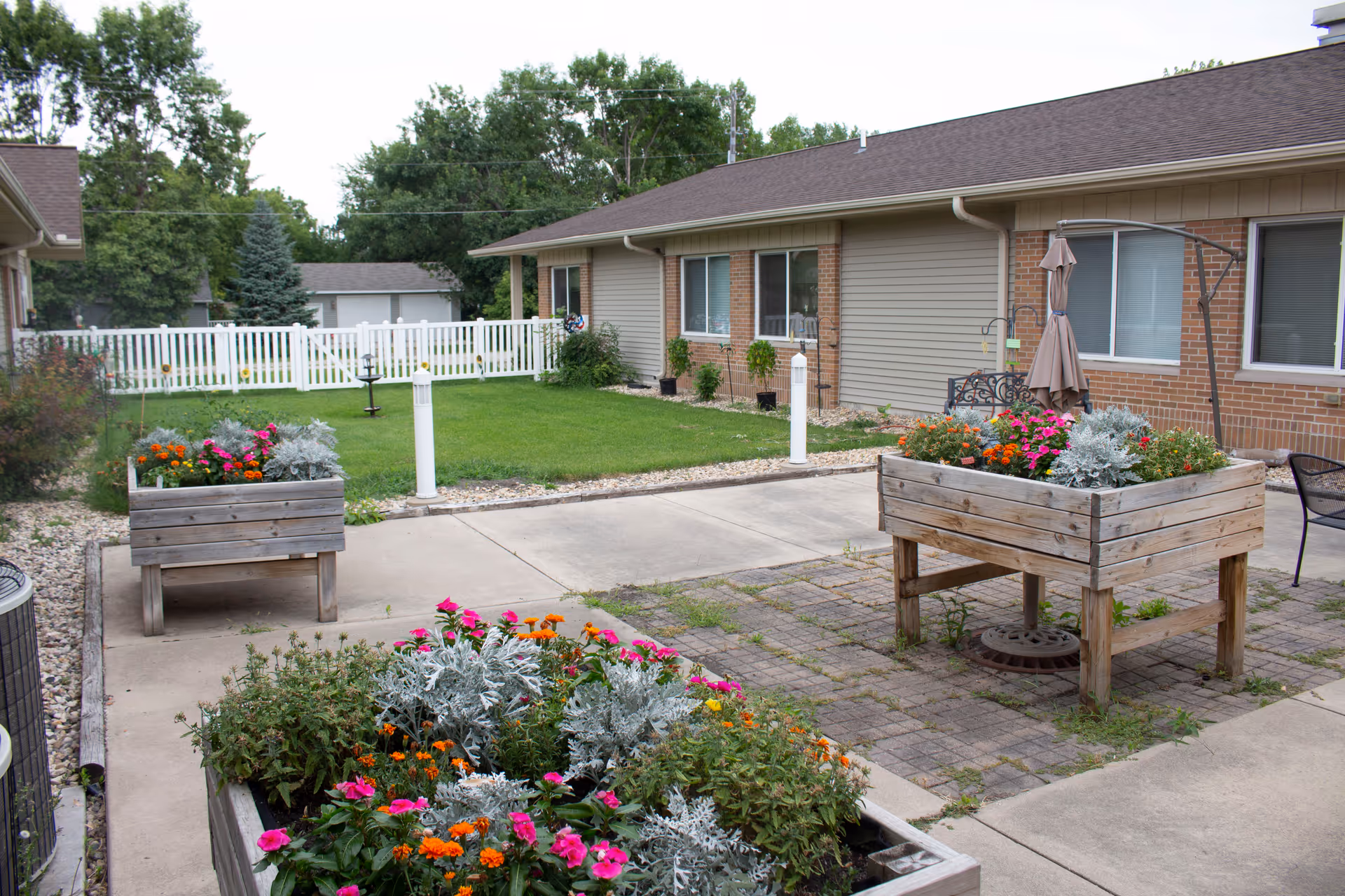 Exterior courtyard of a senior living facility with raised planters and colorful flowers.