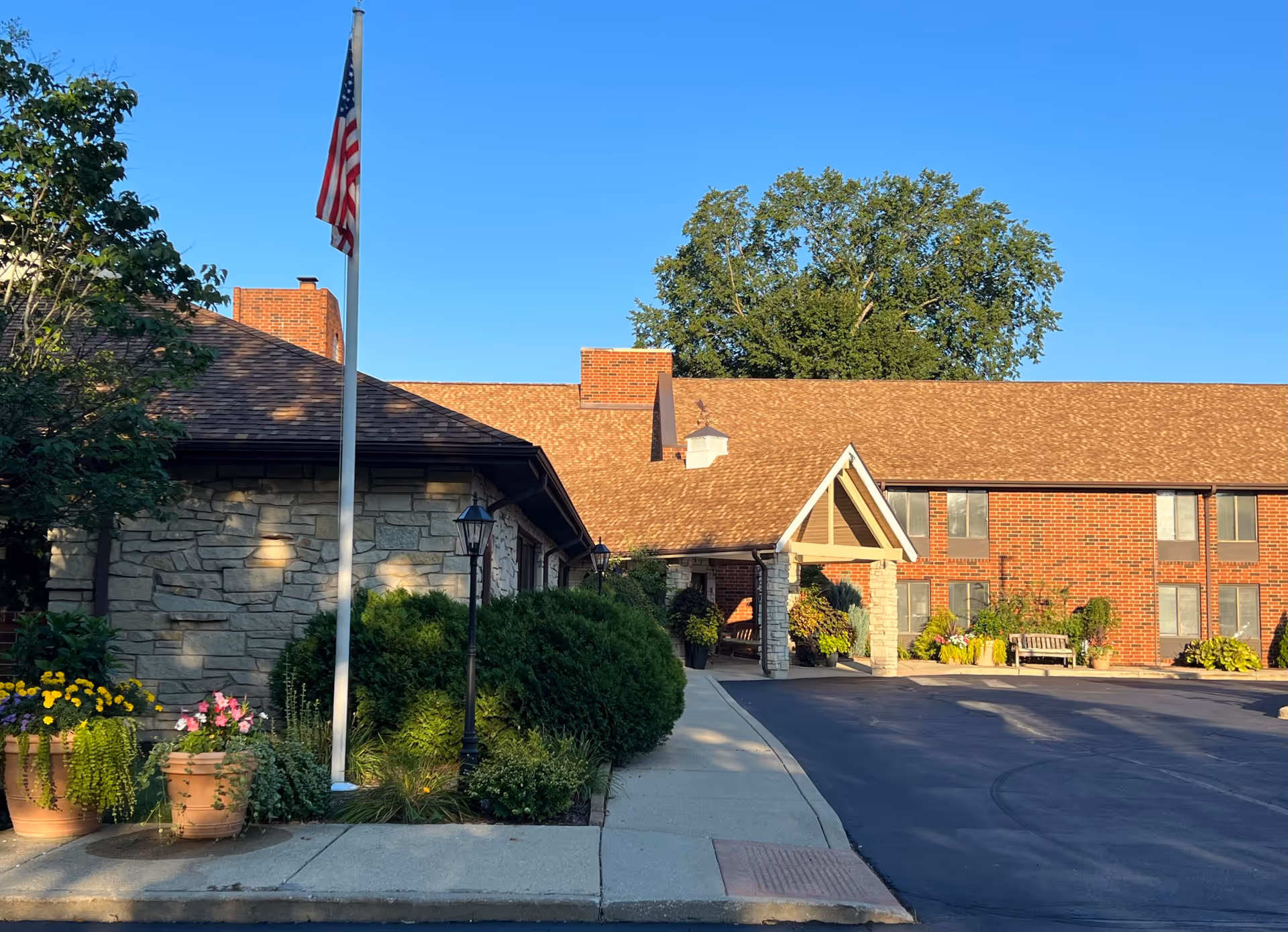 Exterior of Independence Village facility with brick building, covered entrance, flagpole, and landscaped front.