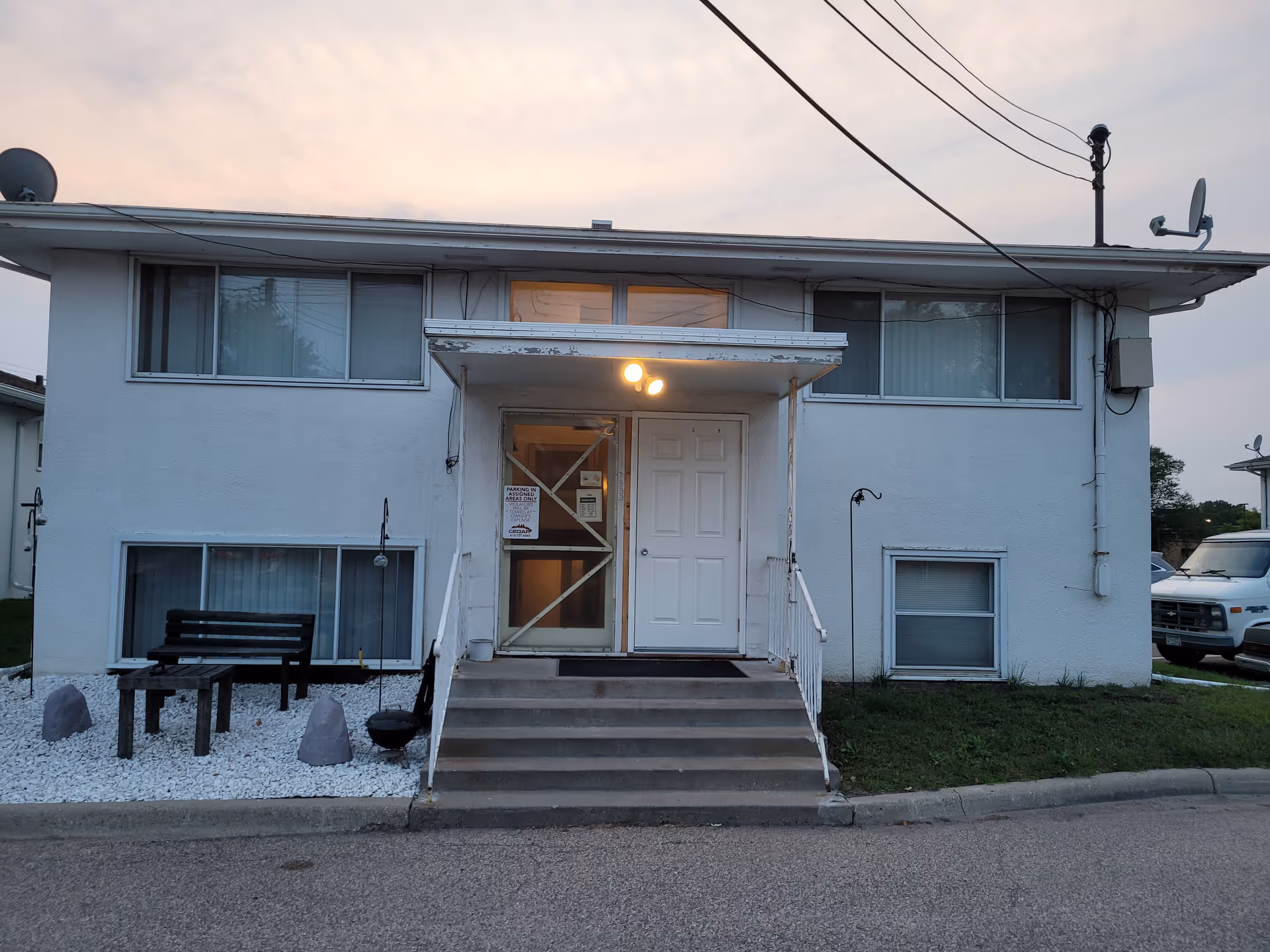 White, two-story facility exterior with central entrance and stairs, no people visible.