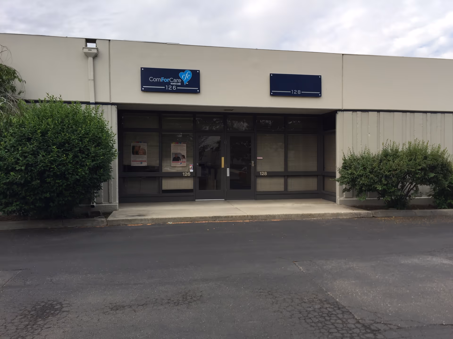 Facade of a ComForCare Home Care building with glass entrance doors and blue signs.