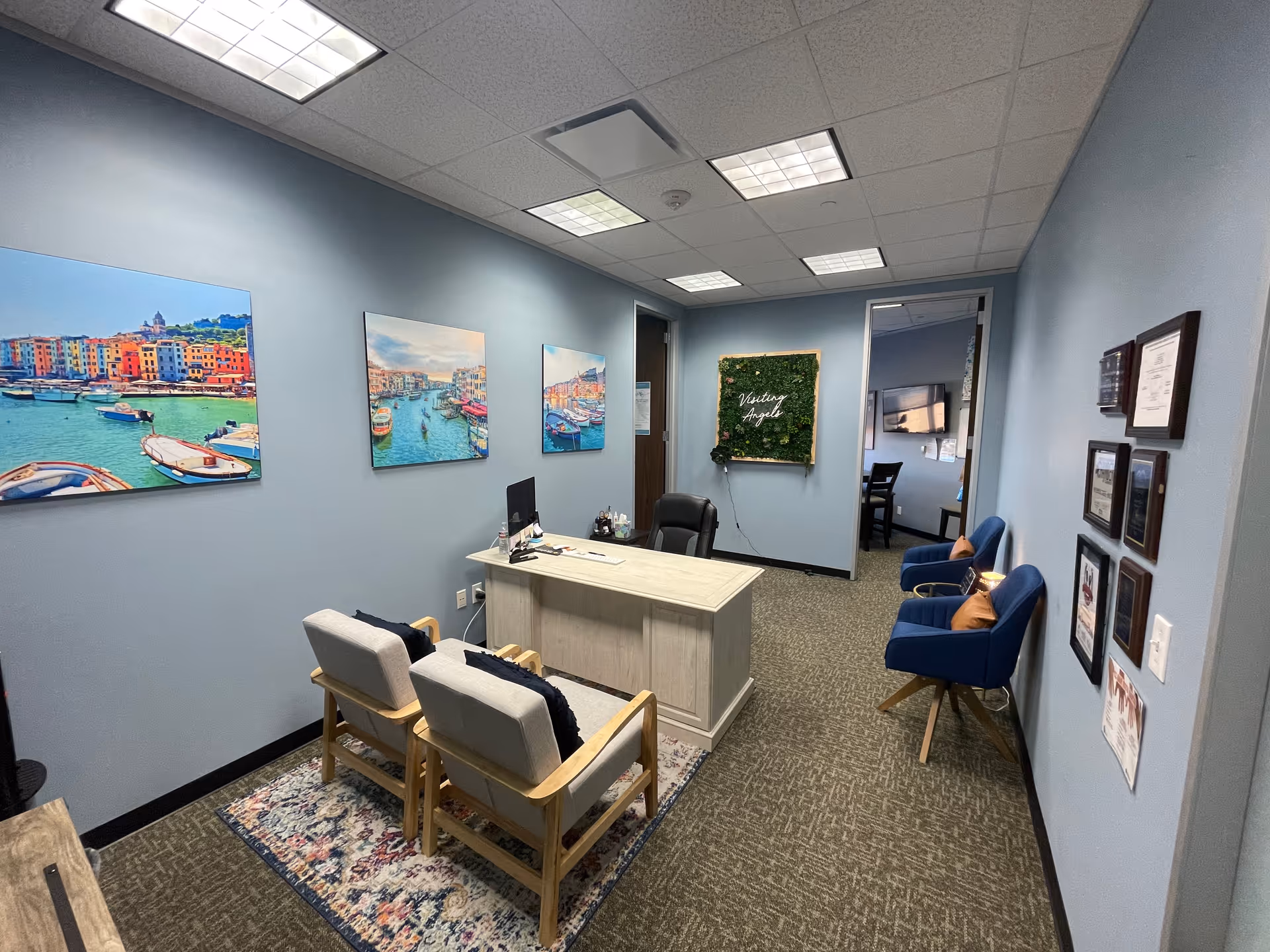 Reception area with desk, blue walls, chairs, and wall art in a senior home care facility.