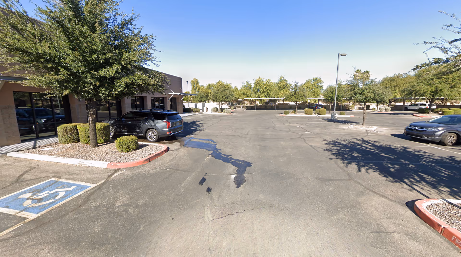 Parking lot in front of a senior care facility with trees and cars.