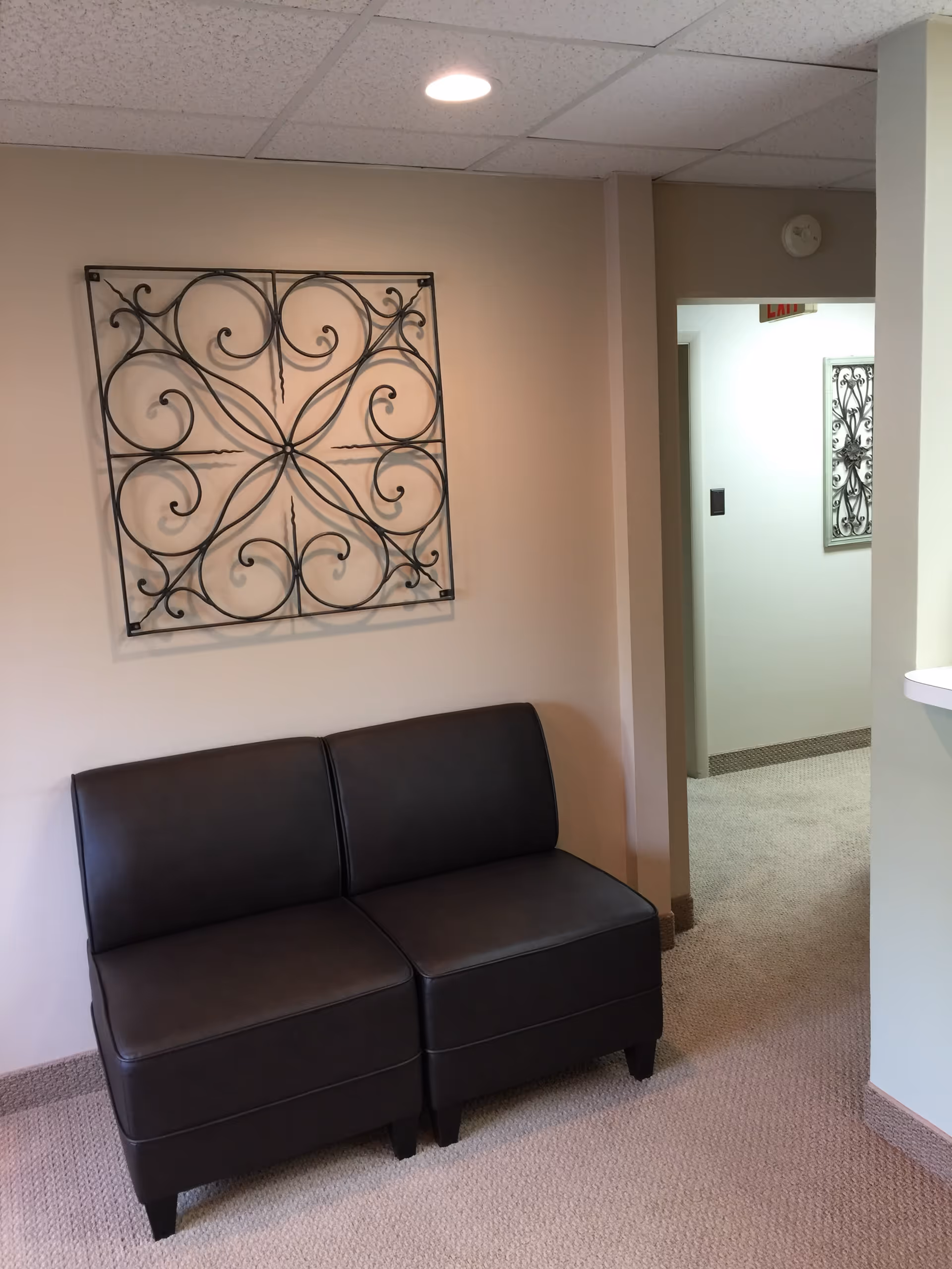 Cozy interior seating area with a black leather loveseat and ornate metal wall art.