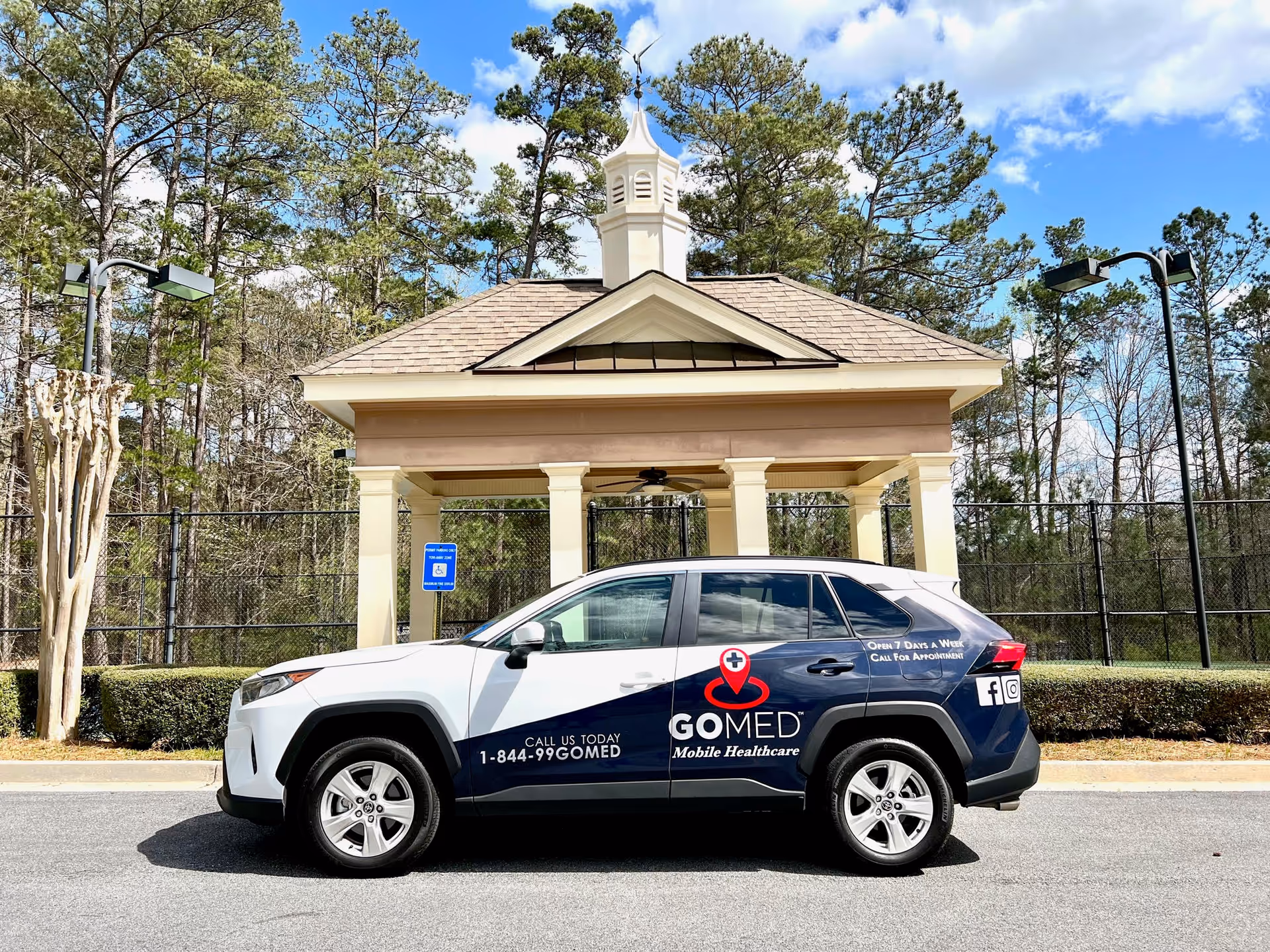 GOMED Mobile Healthcare SUV parked in front of a small pavilion beside trees.