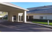 Exterior view of Palm Garden of Pinellas, featuring a covered entrance and lawn.