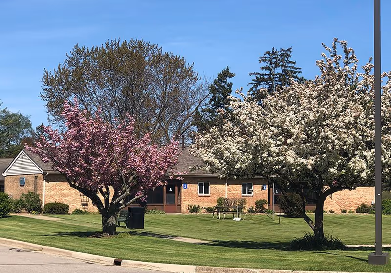 Brick Village of East Harbor senior living facility with blossoming trees in front.