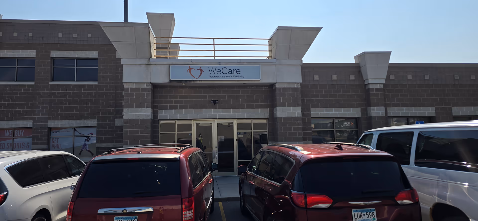 Facade of a WeCare senior living facility with parked cars in front.