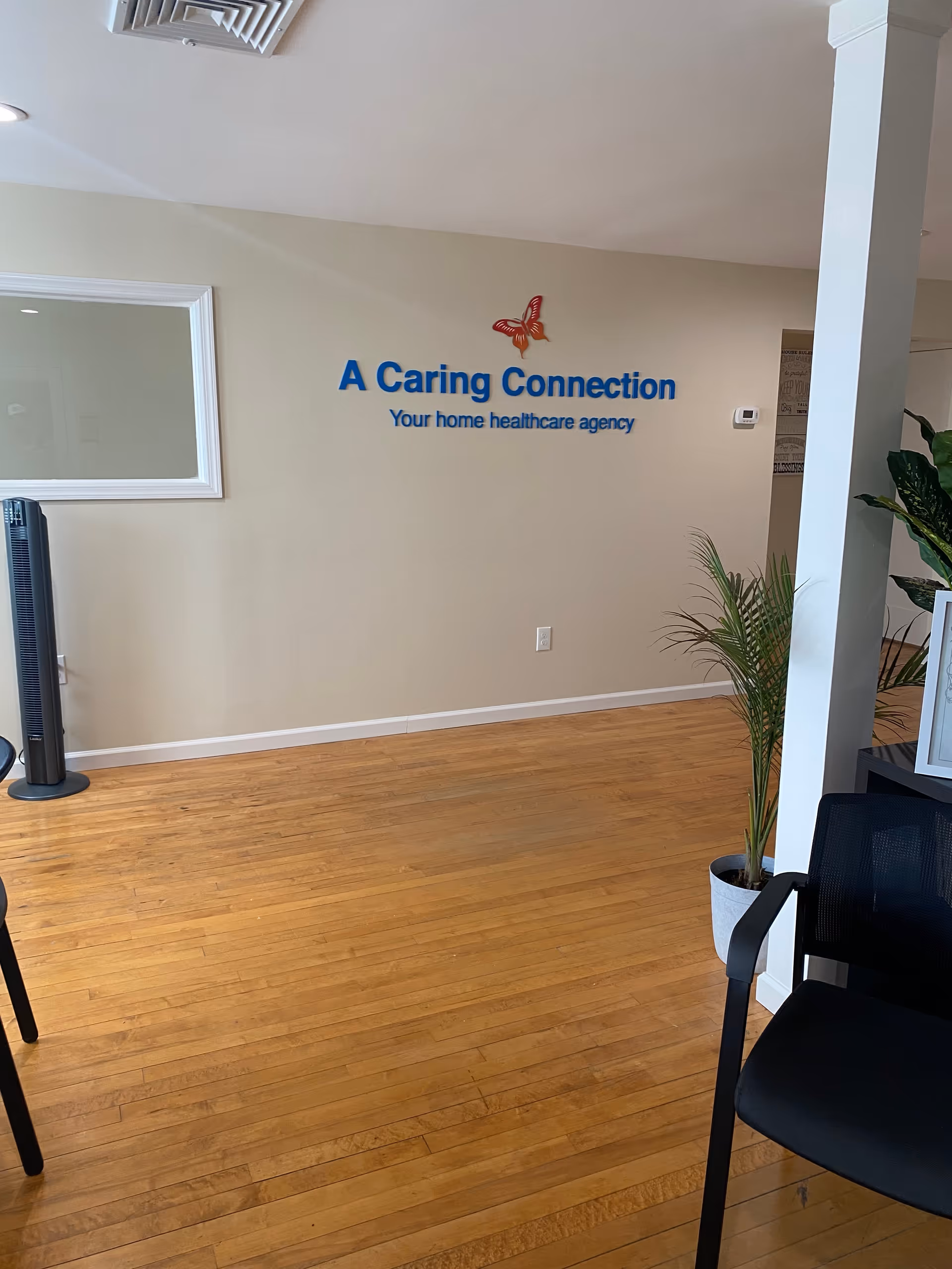 Lobby area with beige walls, a wooden floor, and a blue sign reading A Caring Connection.