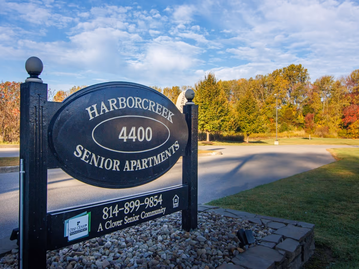 Harborcreek Senior Apartments sign with autumn trees and driveway