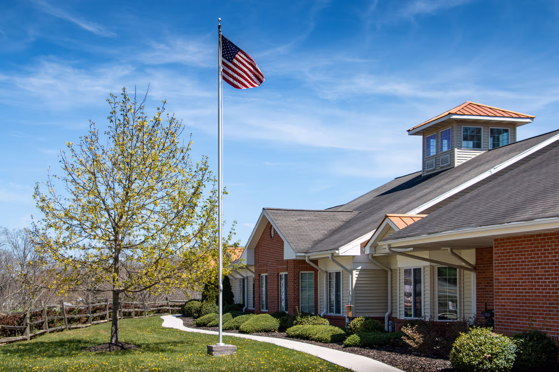 American flag on flagpole in front of Havens at Princeton building with brick exterior.