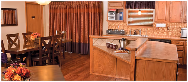Open-concept kitchen and dining area with wooden cabinets, island, and floral centerpiece.