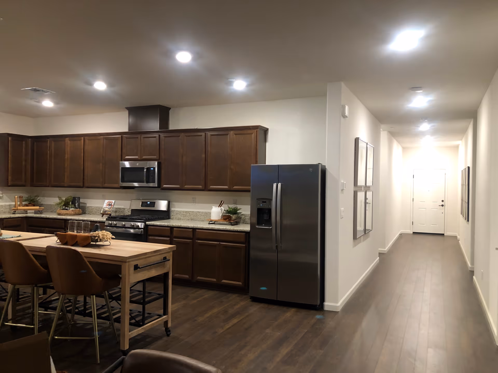 Modern kitchen with dark wood cabinets, stainless appliances, and a wooden island with seating.