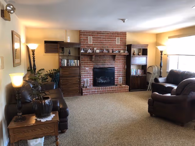 Cozy living room with brick fireplace, bookshelves, and leather seating.