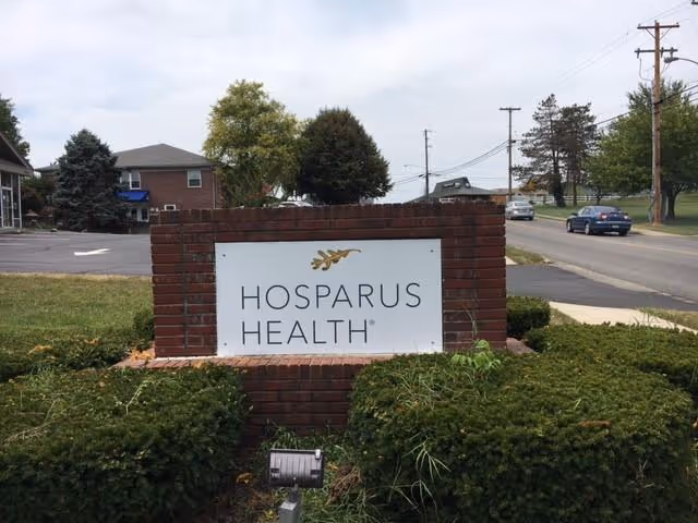 Brick sign reads Hosparus Health in front of a landscaped area by the road.