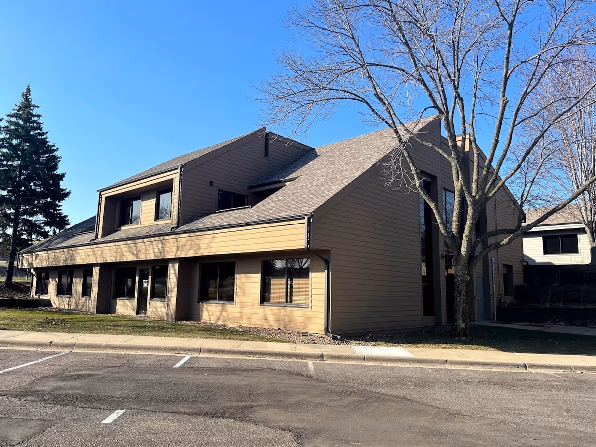 Tan, modern senior living building with large windows and a parking lot.