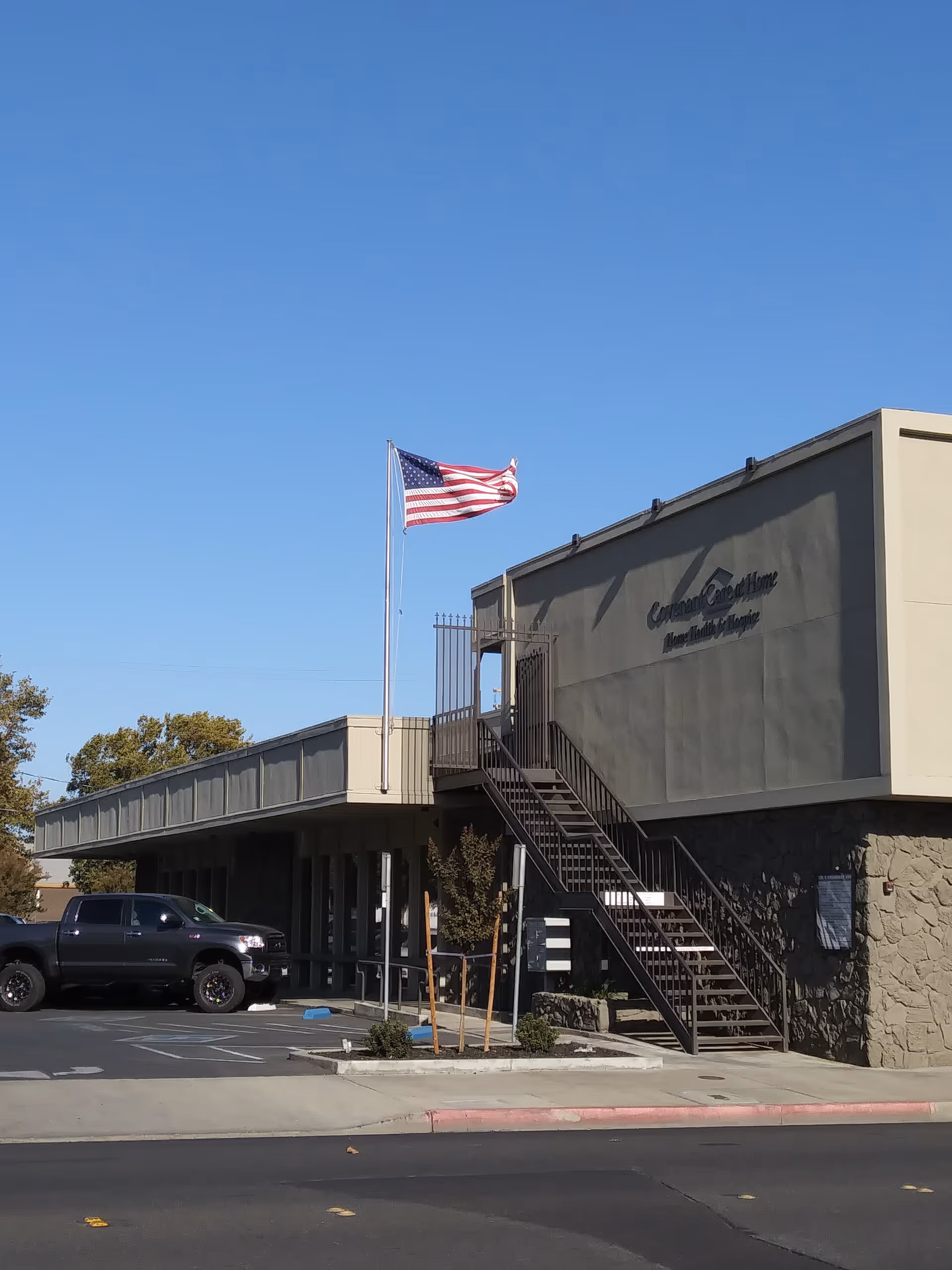 Exterior view of CovenantCare Home Health & Hospice building with an American flag.